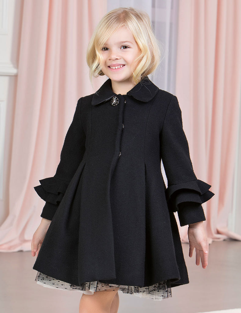 Pretty Young Lady Wearing the Abel & Lula Black Coat in Doors inf Front of a Pink Backdrop 