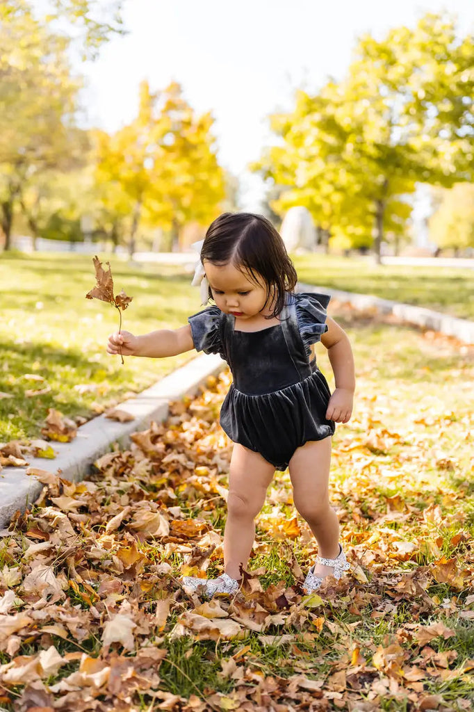 Little Girl in Emmy Romper picking up the leaves.