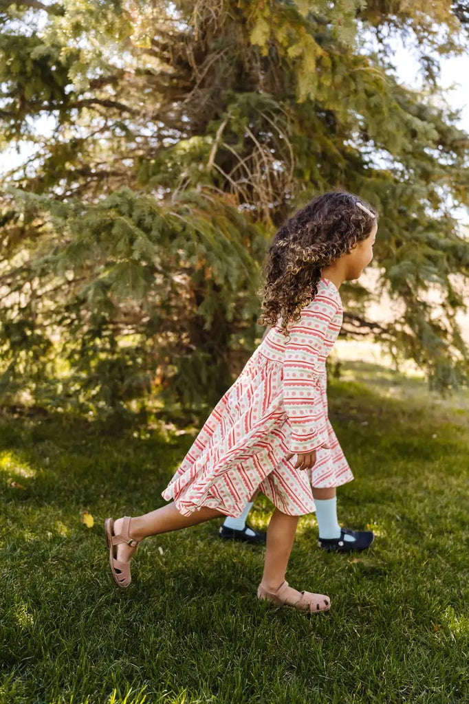 Little girl running around the trees.
