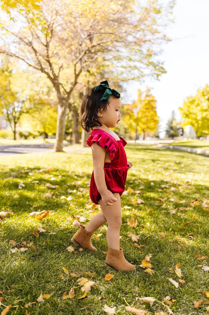 Little Girl Walking to side wearing Emmy Romper In Ruby Velvet