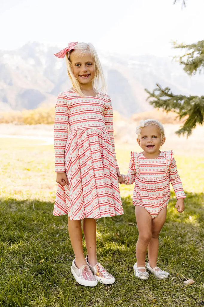 Two little girls holding each other with their matching outfits.