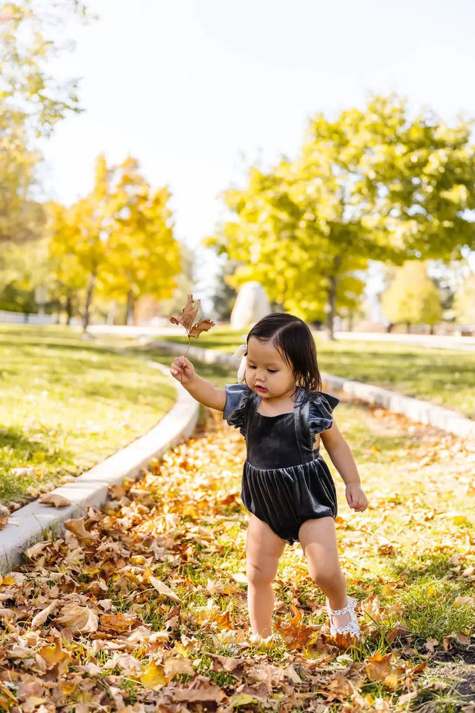 Little Girl in Emmy Romper holding the leaf.