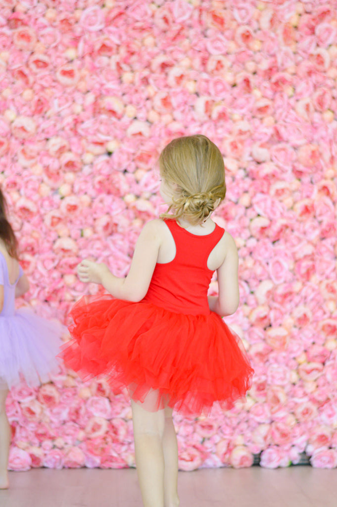 Little Girl Swirling in Red Tutu Dress with Flowery Background