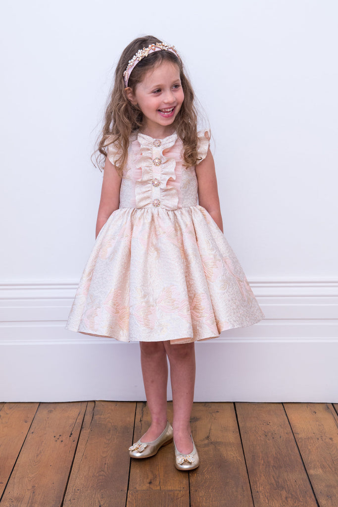 Little Girl looking at her side Wearing David Charles Pink Brocade Dress.