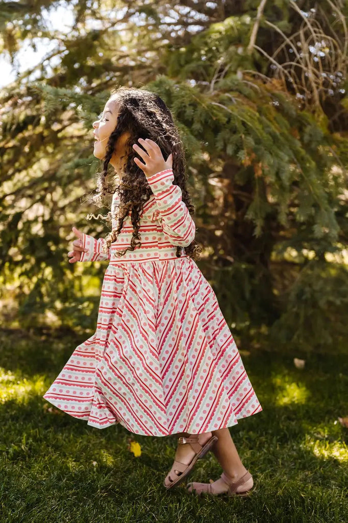 Little Girl posing Side view of her Gwendolyn Dress in Ornamental Stripe.